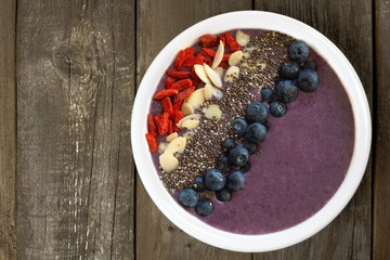 Blueberry smoothie bowl with superfoods on rustic old wood