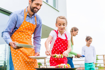 Vater und Tochter grillen zusammen auf Terrasse