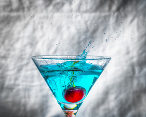 cerise tombant dans un verre de cocktail