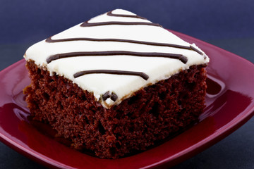 Square slice of red velvet cake on crimson plate