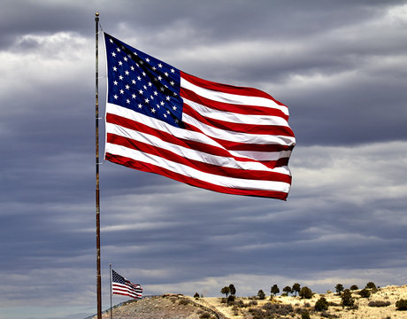Two US Flags Flying against cloudy sky