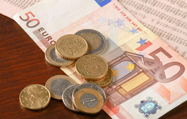 Money: euro coins and bills close up isolated on wood background