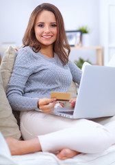 Obraz premium Portrait of happy young woman sitting on sofa