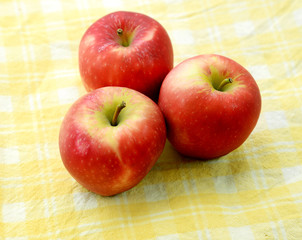 Three apples on checkered tablecloth