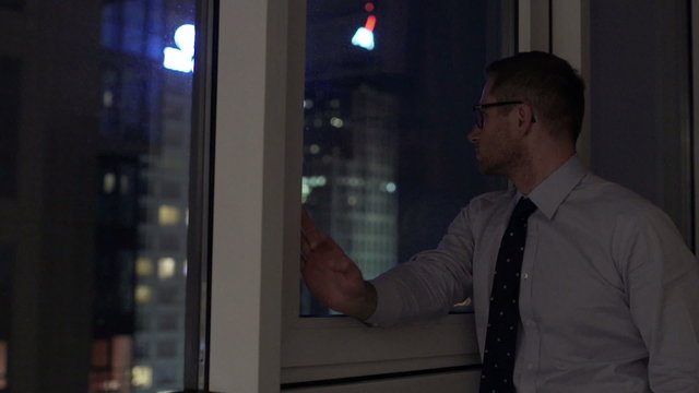 Businessman standing next to the window and looking at night
