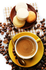 Gentle colorful macaroons and black coffee in mug on white background, top view