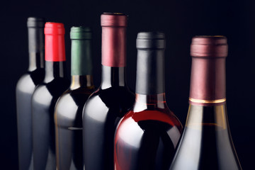 Wine bottles in row on black background