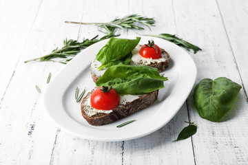 Delicious sandwiches with tomatoes and greens on plate table close up