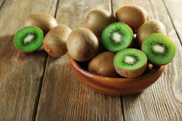 Juicy kiwi fruit in bowl on wooden background