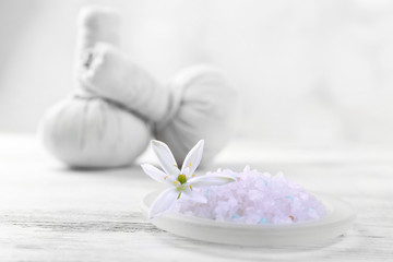 Sea salt, flowers and spa treatment on color wooden table, on light background