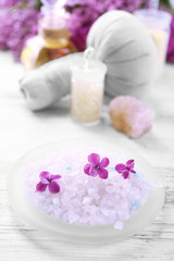 Obraz na płótnie Canvas Sea salt, flowers and spa treatment on color wooden table, on light background