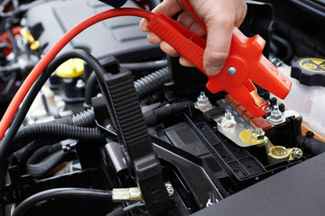 Close-Up Of Mechanic Attaching Jumper Cables To Car Battery