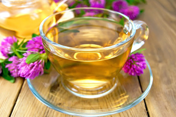 Tea with clover in cup and teapot on board