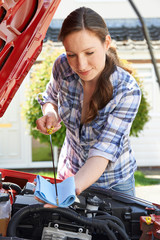 Fototapeta na wymiar Woman Checking Car Engine Oil Level Under Hood With Dipstick