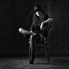 Sexy young woman sitting on a chair on a black background.