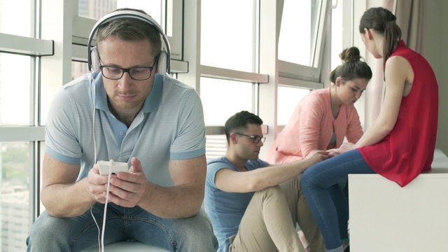Man listening music while his friends chatting
