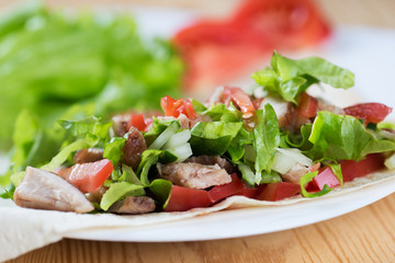 Tortilla with a delicious grilled meat and fresh mixed leafy gre