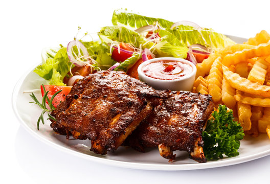 Grilled ribs, French fries and vegetables on white background 