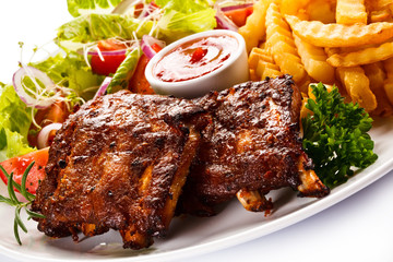 Grilled ribs, French fries and vegetables on white background 
