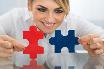 Businesswoman Holding Pieces Of Jigsaw Puzzle