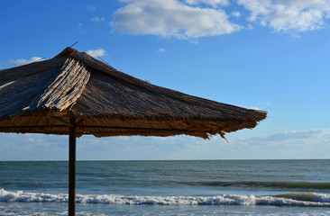Straw Beach Umbrella, sea and blue sky with clouds