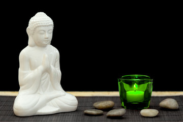 White figure in meditation pose with pebbles and candle