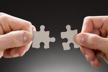 Close-up Of Hands Holding Jigsaw Pieces