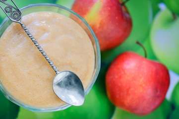 Homemade apple sauce with cinnamon and apple on background.