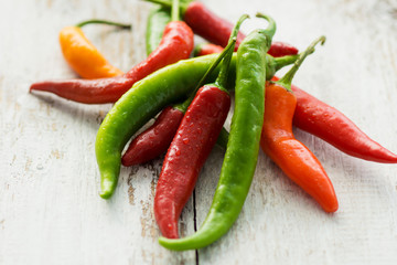 Green and red chilies on a wooden background