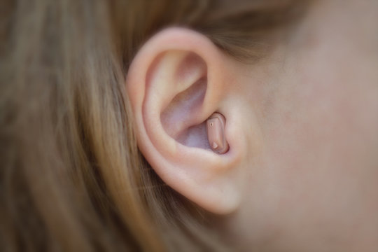 Women's ear with a hearing aid