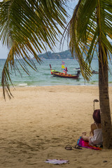 Fototapeta na wymiar Pretty girl enjoys the beautiful Patong Beach shaded by a tree