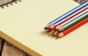 Obraz premium Workspace with colored pencils and notebook on old wooden table