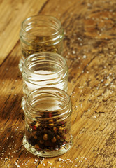 Spices: salt, pepper and herbs in small glass jar on a wooden ta