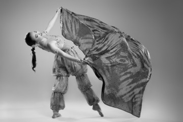 Beautiful young woman in a dress dancing in the studio