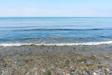 gentle Sea surf on a beach of pebbles, horizon and blue sky, fro