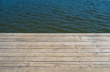 Fototapeta premium Wooden deck by water, background with copy space