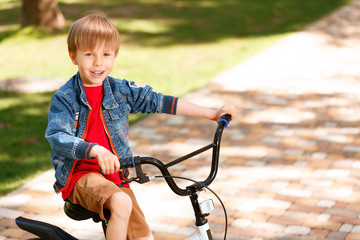 Small smiling boy riding bike.