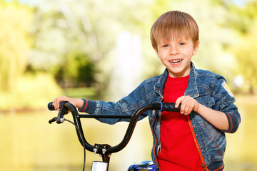 Fototapeta na wymiar Close up of smiling boy standing near bike