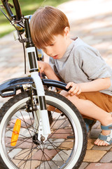 Fototapeta na wymiar Close up of little boy repairing his bike 