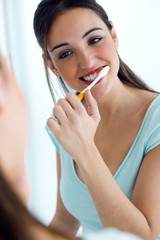 Pretty young woman brushing her teeth.