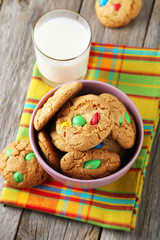 Cookies with colorful candy in bowl on grey wooden background