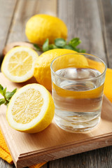 Lemons on cutting board with glass of water on grey wooden backg