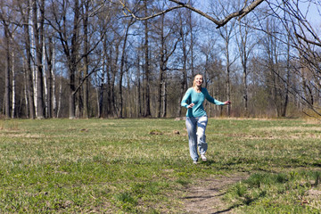 The woman runs on the track in the spring wood