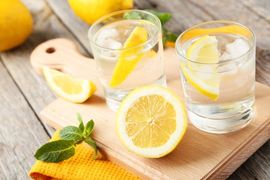 Fresh lemonade with lemon on grey wooden background