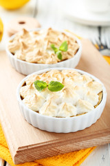 Lemon meringue pie in bowl on white wooden background