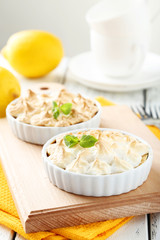 Lemon meringue pie in bowl on white wooden background
