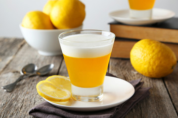 Tasty lemon jelly in glass on grey wooden background