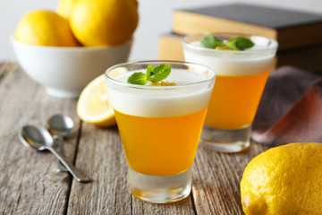 Tasty lemon jelly in glass on grey wooden background