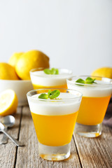 Tasty lemon jelly in glass on grey wooden background