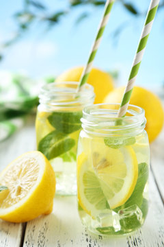 Fresh lemonade with lemon on white wooden background